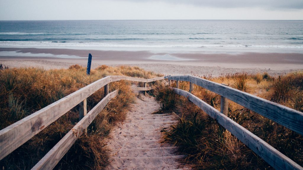 Foto van houten trap die naar strand leidt